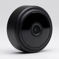 Mini round black wireless security camera on a studio background
