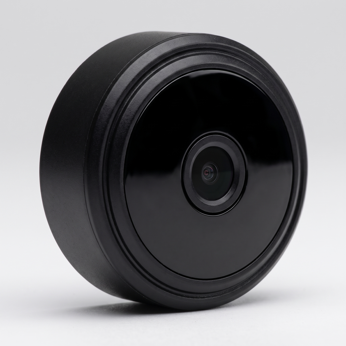 Mini round black wireless security camera on a studio background
